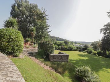 A garden with stone steps bushes and trees overlooking fields at The Croft in Vowchurch near Peterchurch