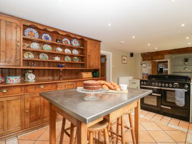 A kitchen with a table, oven, and shelves at The Croft in Vowchurch near Peterchurch