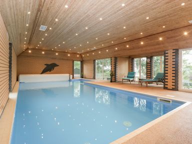 An indoor pool area with chairs and large windows at The Croft in Vowchurch near Peterchurch