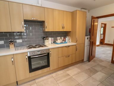 A kitchen with wooden cabinets tiled floor and a countertop with utensils and appliances at Hill Farm Cottage Kerry's Gate near Abbey Dore