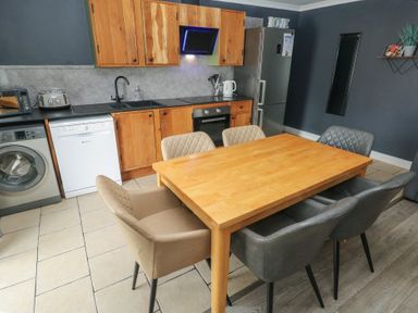 A kitchen with a dining table and appliances at Dylan's Court in Laugharne