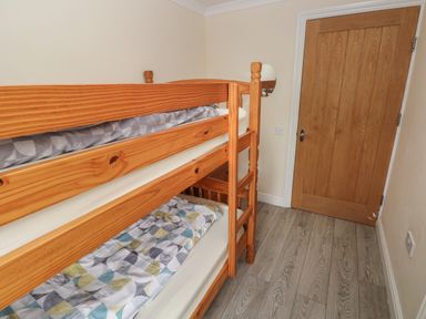 A small bedroom with wooden bunk beds and a wooden door at Barn Cottage in Laugharne