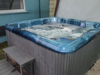 An outdoor hot tub with bubbling water next to a small wooden bench at Barn Cottage in Laugharne