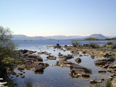 A rocky shoreline with water and hills in the background at Clooncorraun Cottage in Ballinrobe County Mayo