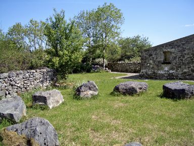 A grassy outdoor area with large rocks trees and stone walls at Clooncorraun Cottage in Ballinrobe County Mayo