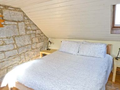 A bedroom with a double bed and stone wall at Clooncorraun Cottage in Ballinrobe County Mayo