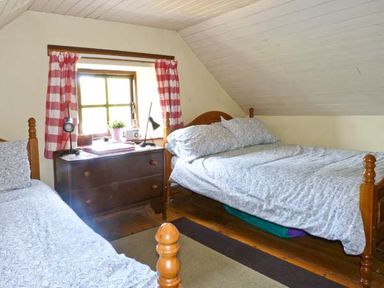 A bedroom with two single beds a dresser and a window with red and white check curtains at Clooncorraun Cottage Ballinrobe County Mayo