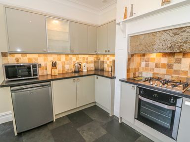 A kitchen with cabinets a microwave a kettle a gas stove and oven at Riverside View in Cark in Cartmel