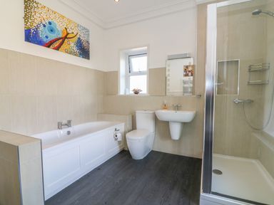 A bathroom with a bathtub toilet sink shower and a window at Riverside View in Cark in Cartmel