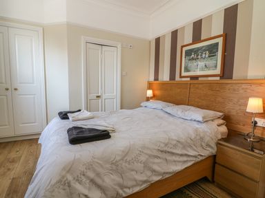 A bedroom with a double bed bedside tables lamps and a painting above the bed at Riverside View in Cark in Cartmel