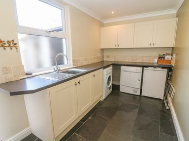 A utility room with a sink washing machine dishwasher and small fridge at Riverside View in Cark in Cartmel
