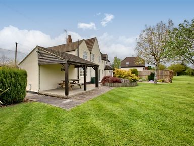Garden area with a covered patio and picnic table next to a two-story house with lawn and trees at Ingleside in Adsett Royal Forest of Dean