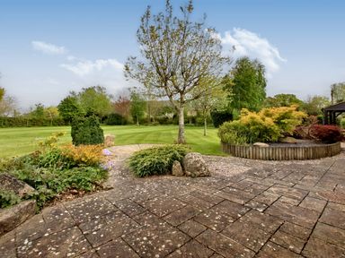 A garden with a paved patio area a tree flower beds and a large grassy lawn at Ingleside in Adsett Royal Forest of Dean