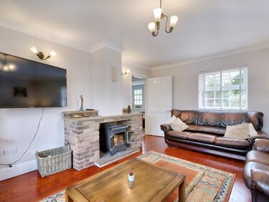 A living room with a fireplace a wall mounted television and leather sofas at Ingleside in Adsett Royal Forest of Dean