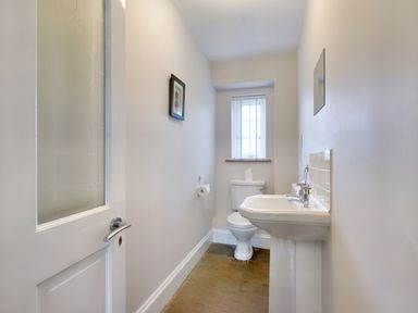 A narrow bathroom with a toilet sink a window and a door at Ingleside in Adsett Royal Forest of Dean