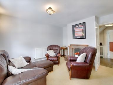 A living room with brown leather chairs a fireplace and framed shirt on wall at Ingleside Adsett Royal Forest of Dean
