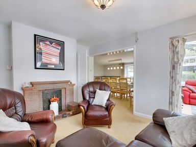 A living room with leather armchairs a brick fireplace and a dining area visible through an open doorway at Ingleside in Adsett Royal Forest of Dean