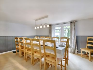 A dining room with a long wooden table and chairs set with plates and bowls at Ingleside in Adsett Royal Forest of Dean