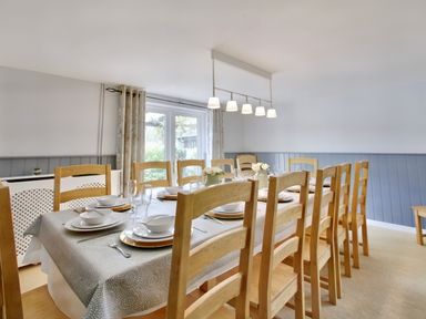 A dining room with a long table set with plates bowls glasses and wooden chairs at Ingleside in Adsett Royal Forest of Dean