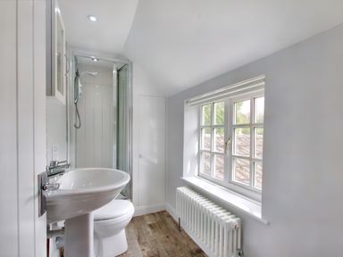 A bathroom with a sink toilet shower and window with radiator below at Ingleside in Adsett Royal Forest of Dean