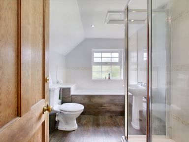 A bathroom with a wooden door toilet bathtub shower and sink at Ingleside in Adsett Royal Forest of Dean
