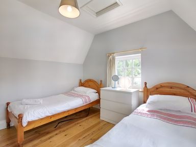 A bedroom with two single wooden frame beds a white dresser and a window at Ingleside in Adsett Royal Forest of Dean