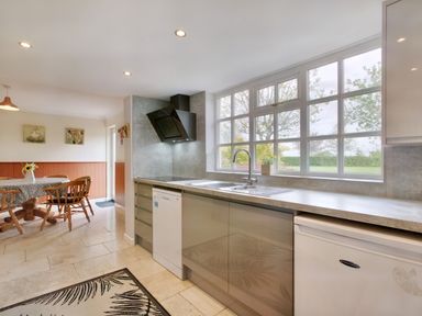 A kitchen with a sink under large windows and a dining area with a round table and chairs at Ingleside Adsett Royal Forest of Dean