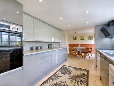 A kitchen with modern cabinets countertops and appliances a dining area with a table and chairs at Ingleside in Adsett Royal Forest of Dean