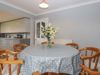 A dining area with a round table covered by a polka dot tablecloth and wooden chairs around it at Ingleside in Adsett Royal Forest of Dean