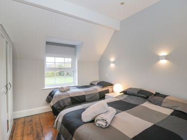 A bedroom with two single beds a white nightstand a round lamp and a window at Ingleside in Adsett Royal Forest of Dean