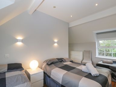 A bedroom with three beds a white bedside table with a lamp a white dresser and a window at Ingleside in Adsett Royal Forest of Dean