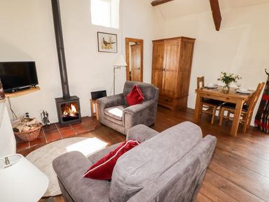 A living room with two armchairs a wood stove and a dining table at The Old Stable in Wolfscastle near Haverfordwest