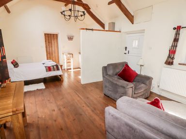 An open room with armchairs and a bed with towels on wooden floorboards at The Old Stable in Wolfscastle near Haverfordwest