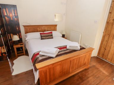 A bedroom with a wooden bed and bedside tables with lamps at The Old Stable in Wolfscastle near Haverfordwest
