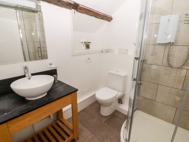 A bathroom with a sink on a wooden vanity a toilet and a glass shower enclosure at The Old Stable in Wolfscastle near Haverfordwest