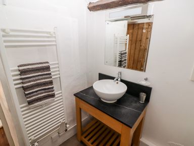 A bathroom with a wooden sink cabinet and a round white sink at The Old Stable in Wolfscastle near Haverfordwest