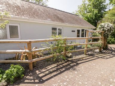 The exterior of a single story building with a wooden fence and plants in front at The Duck House in Wolfscastle