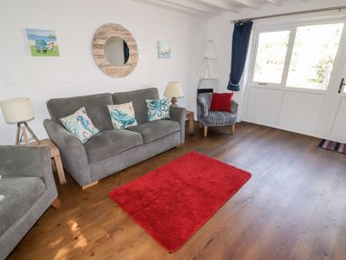 A living room with grey sofas and a red rug on wooden floor at The Duck House in Wolfscastle