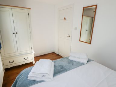 A bedroom with a bed covered by towels a blanket and a white wardrobe and mirror on the wall at The Duck House in Wolfscastle