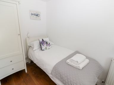 A small bedroom with a single bed a white wardrobe and folded towels at The Duck House in Wolfscastle