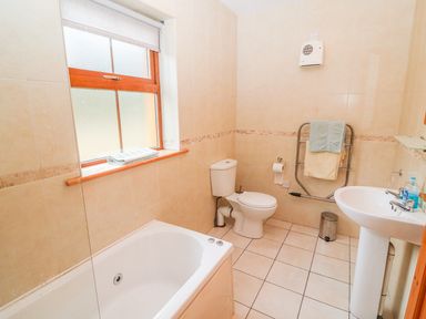 A bathroom with a bathtub toilet sink towel rack and window at Mary Agnes Cottage in Cahirkeen near Allihies County Cork