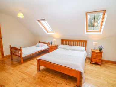 A bedroom with a double bed and a single bed wooden furniture and skylight windows at Mary Agnes Cottage in Cahirkeen near Allihies County Cork