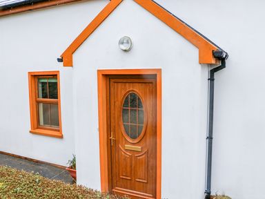 A white house exterior with an orange framed wooden door and window at Mary Agnes Cottage in Cahirkeen near Allihies County Cork