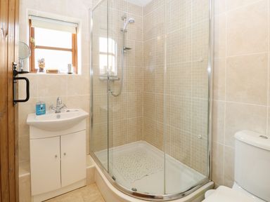 A bathroom with a glass enclosed shower a white sink cabinet and a toilet at The Haybarn in Necton near Swaffham