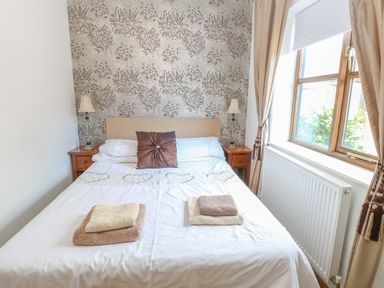 A bedroom with a double bed two bedside tables lamps and a window at The Haybarn in Necton near Swaffham