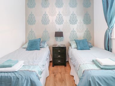 A bedroom with two single beds separated by a black nightstand with a lamp at The Haybarn in Necton near Swaffham