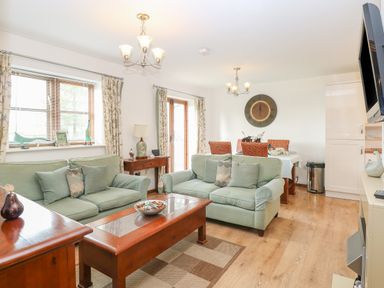 A living room with green sofas wooden tables and dining area at The Haybarn in Necton near Swaffham