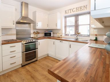 A kitchen with stove microwave sink and wooden countertops at The Haybarn Necton near Swaffham