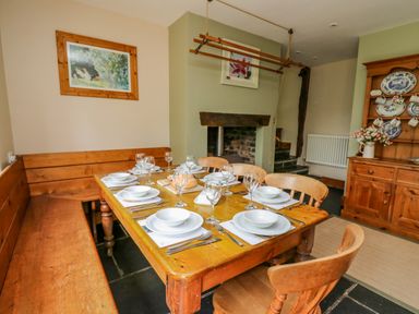 A dining room with a wooden table set for eight with bowls and glasses Byrdir Cottage Rhayader