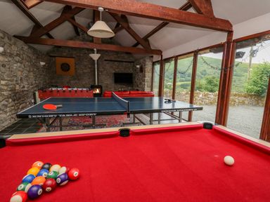 A games room with a red pool table a ping pong table and a foosball table at Byrdir Cottage in Rhayader